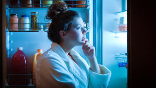 Eine Frau steht im Dunkeln vor dem Kühlschrank