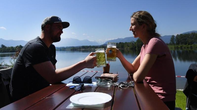Ein Paar genießt ein gemeinsames Bier in der Sonne in einem Biergarten