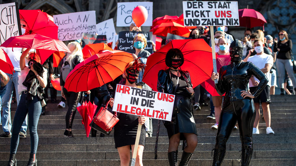 29.07.2020, Nordrhein-Westfalen, Köln: Eine Domina hält während einer Demonstration von Sexarbeiterinnen ein Schild mit der Aufschrift «Der Staat fickt uns und zahlt nix». Die Sexarbeiter demonstrierten gegen das Arbeitsverbot wegen Corona. Trotz Cor