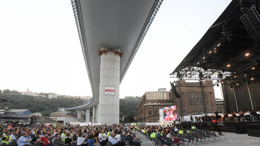 27.07.2020, Italien, Genua: Dirigent Antonio Pappano (r) dirigiert das Orchester der Akademie Nazionale di Santa Cecilia am Fuß des Bauwerks der neuen Autobahnbrücke in der italienischen Hafenstadt Genua. Eine Woche vor der feierlichen Eröffnung der