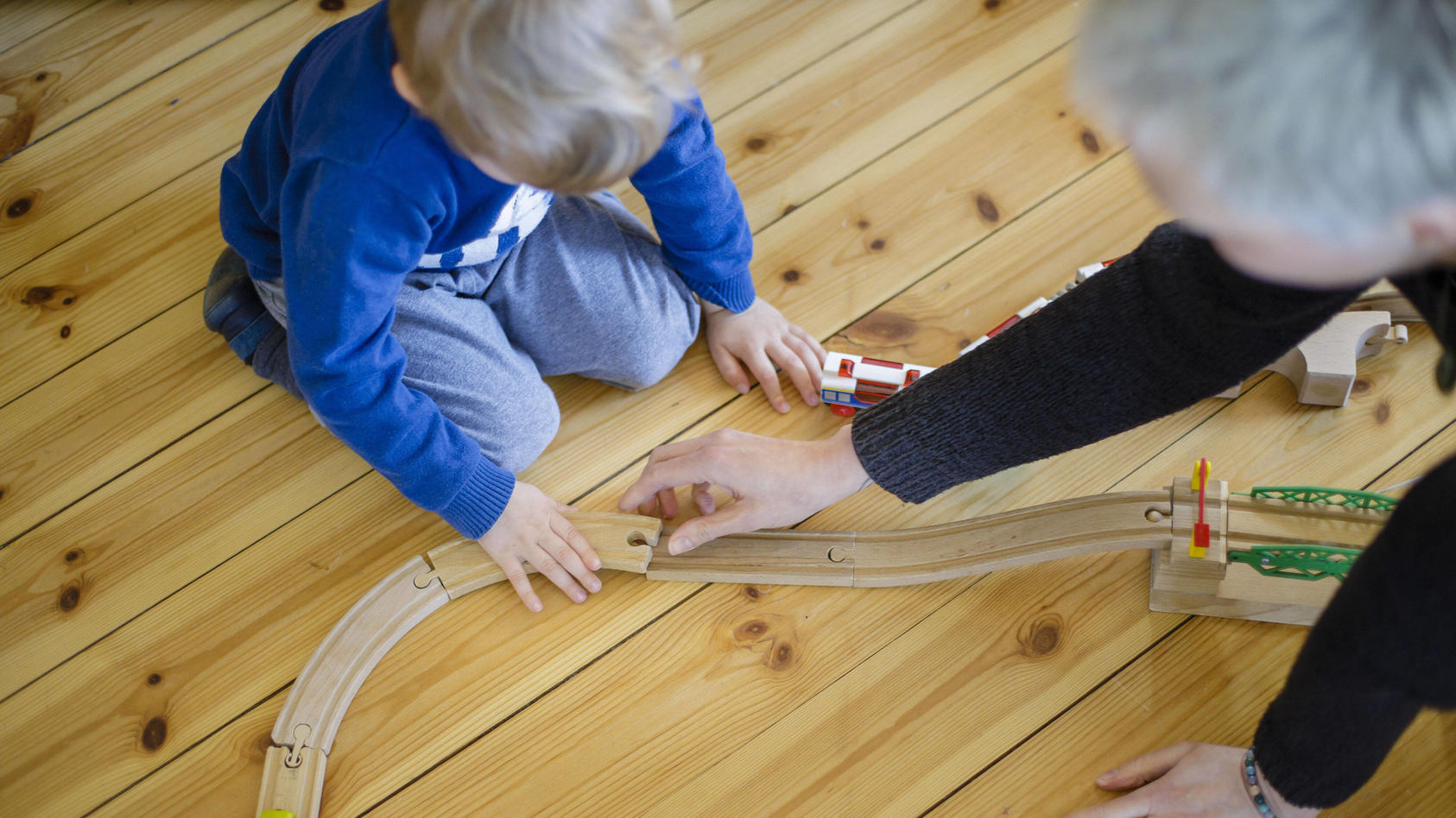 Symbolfoto: Ein Kleinkind und eine Frau spielen auf dem Fussboden mit einer Holzeisenbahn. Berlin, 25.03.2020. Um die Ausbreitung des Coronavirus, COVID-19, SARS-CoV-2 zu verlangsamen, wurden in Deutschland Kindertagesstaetten geschlossen und Kinder
