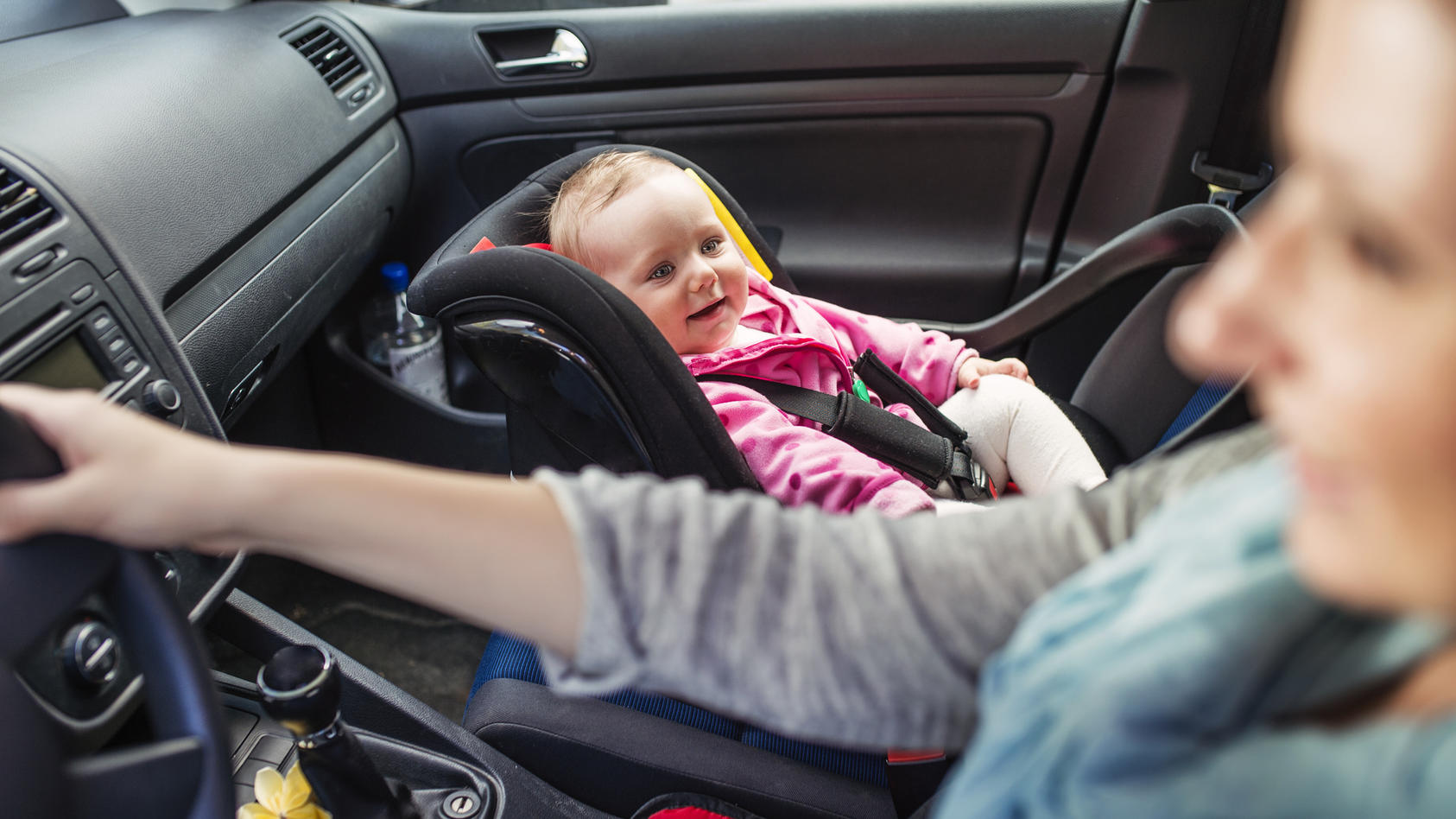 Mutter im Auto mit Baby im Kindersitz