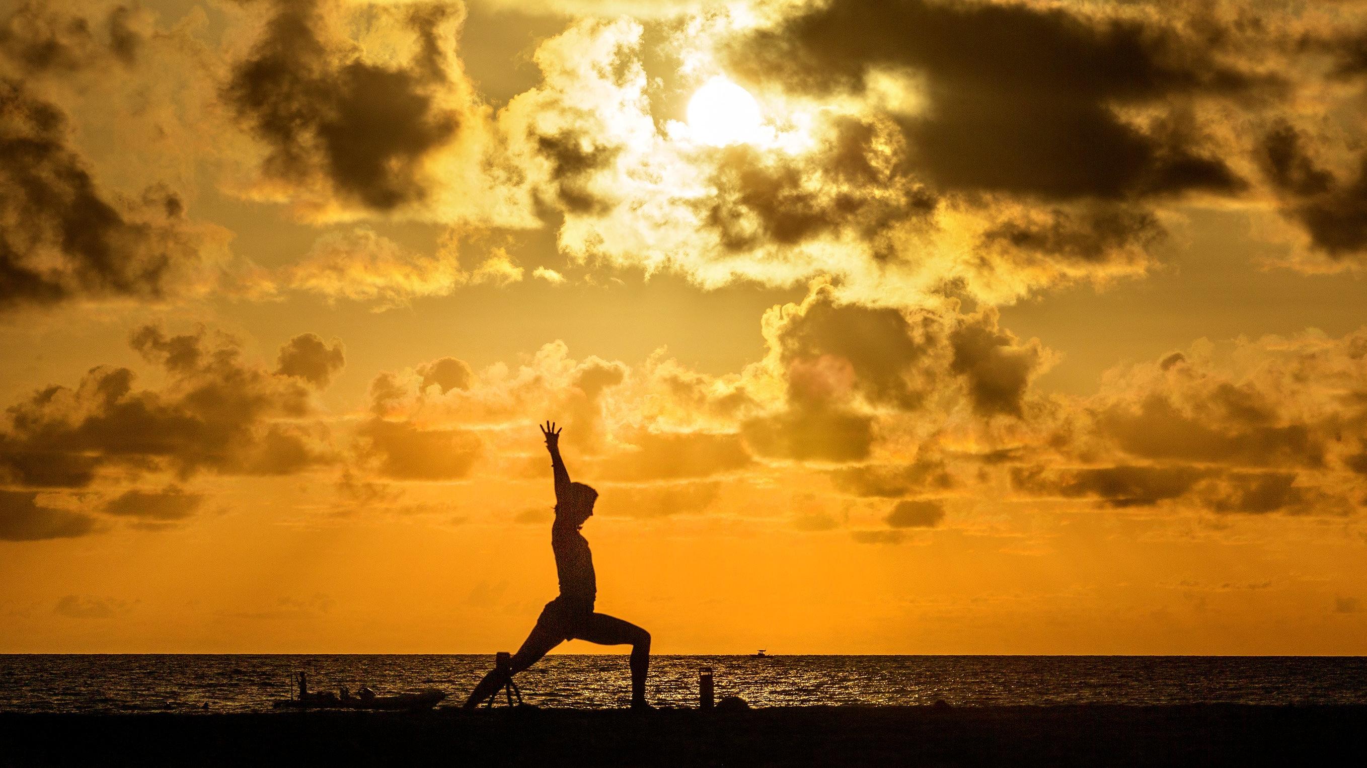 30.07.2020, USA, Palm Beach: Eine Frau macht am Midtown Beach bei Sonnenaufgang Yoga. Foto: Lannis Waters/Palm Beach Post via ZUMA Wire/dpa +++ dpa-Bildfunk +++