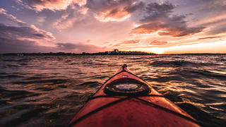POV from red kayak during vibrant sunset in Portland harbor, Maine Portland, ME, United States PUBLICATIONxINxGERxSUIxAUTxONLY CR_SSNF200715B-449750-01