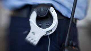 Handschellen hängen am Gürtel eines Justizbeamten