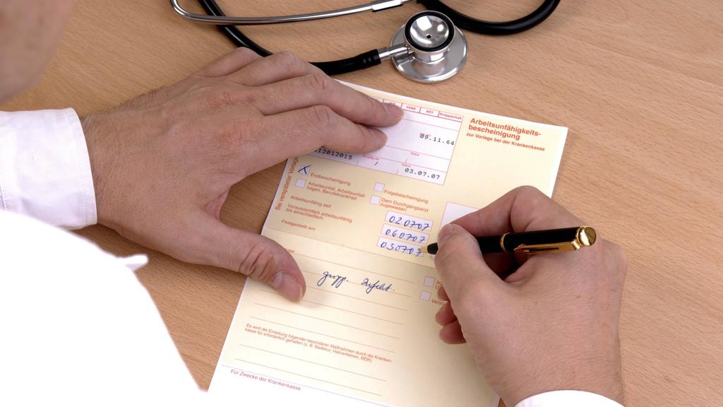 Arzt füllt Arbeitsunfähigkeitsbescheinigung aus