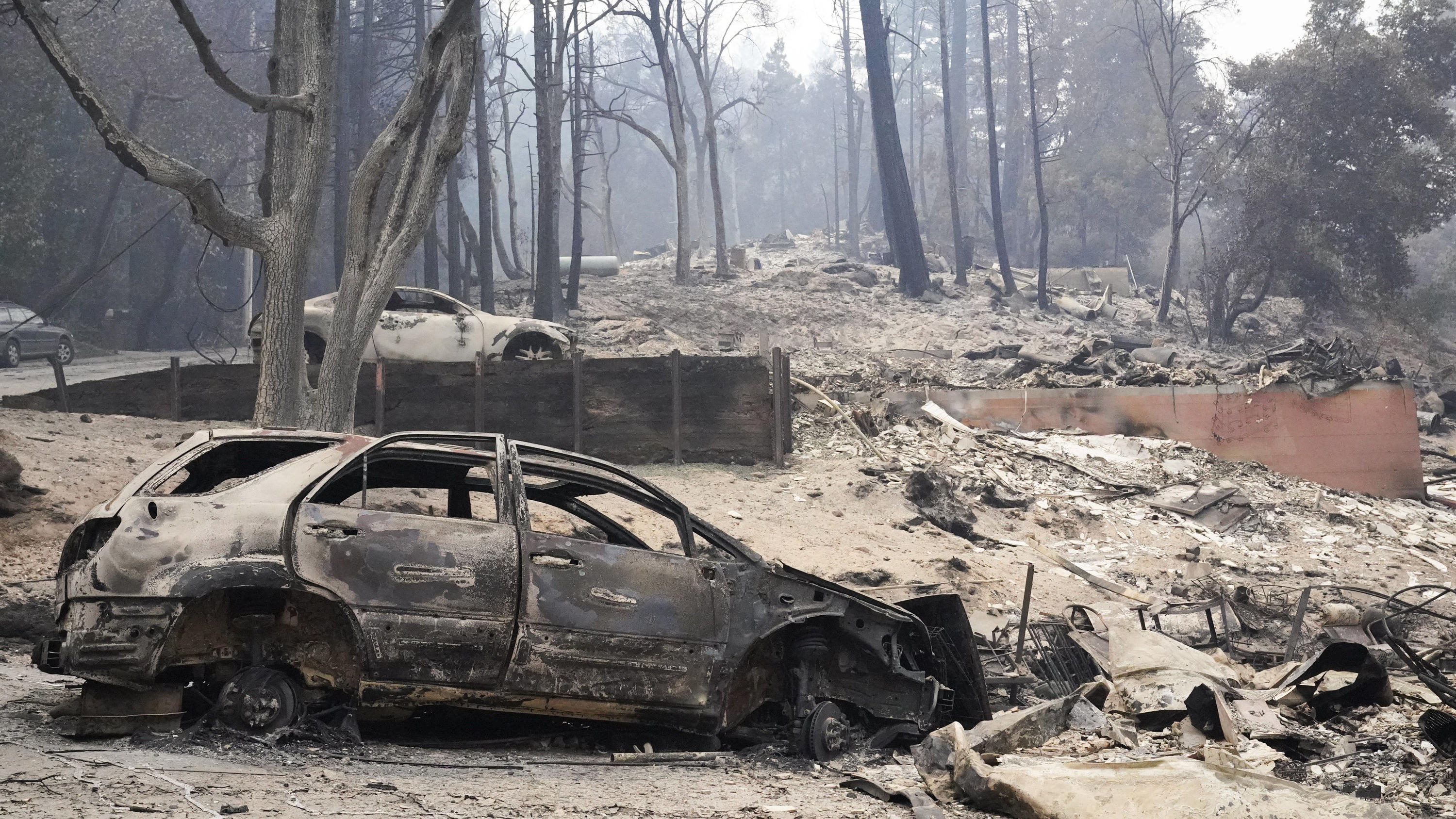 23.08.2020, USA, Boulder Creek: Ein verkohltes Fahrzeug steht nach den verheerenden Waldbränden in Kalifornien neben einem völlig zerstörtem Haus. Nach heftigen Unwettern mit mehr als 12 000 Blitzeinschlägen haben Brände im US-Bundesstaat Kalifornien