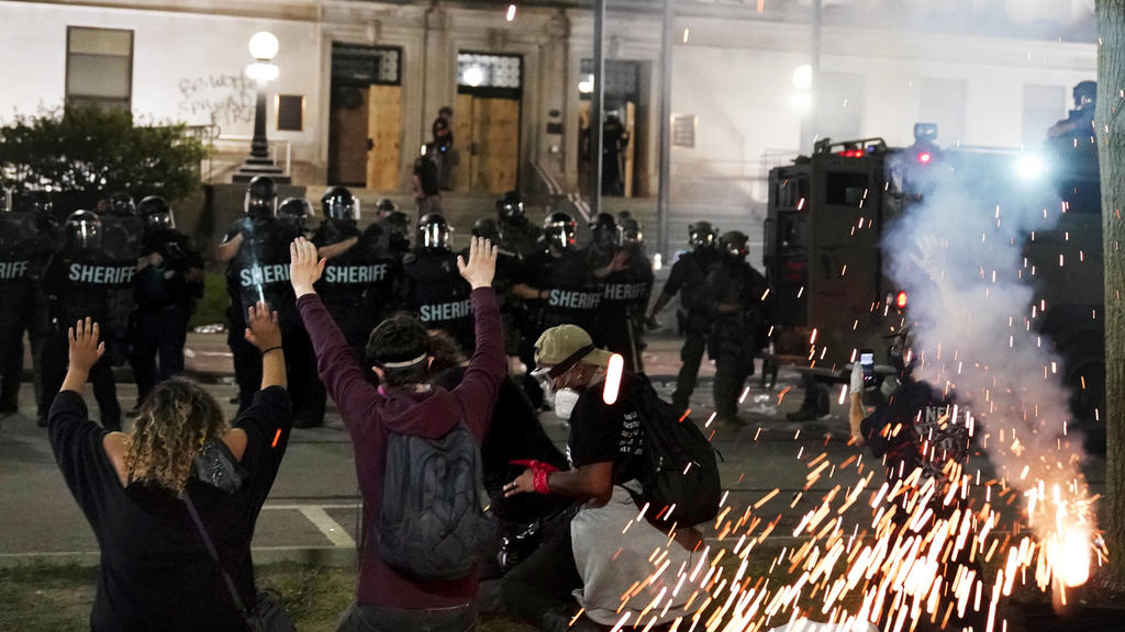 Police attempt to push back protesters outside the Kenosha County Courthouse, late Monday, Aug. 24, 2020, in Kenosha, Wis. Protesters converged on the county courthouse during a second night of clashes after the police shooting of Jacob Blake a day e