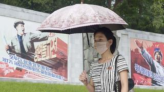 Frau mit Schirm und Maske in Nordkorea.