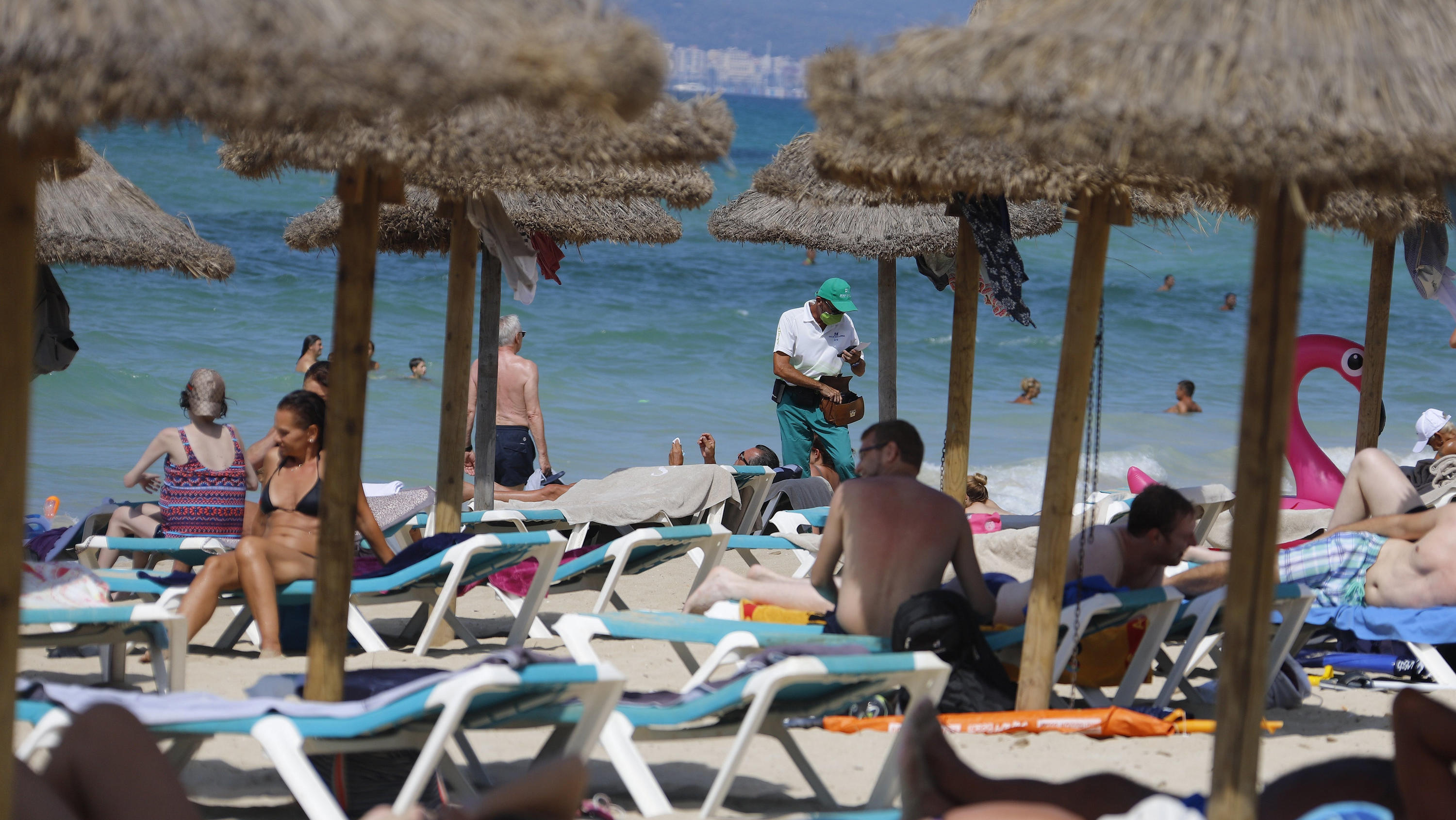 15.08.2020, Spanien, Palma: Menschen sonnen sich und schwimmen am Strand von Arenal auf Mallorca. Angesichts erhöhter Ansteckungsgefahren hat die Bundesregierung fast ganz Spanien einschließlich Mallorca als Risikogebiet eingestuft. Die Einstufung be