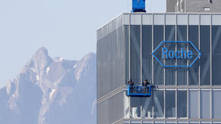 FILE PHOTO: The peak of Mount Pilatus is seen in the background as workers clean the windows of a building of Roche in Rotkreuz May 27, 2020. REUTERS/Arnd Wiegmann/File Photo