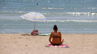 18.08.2020, Spanien, Palma: Eine Frau sonnt sich am Strand von Can Pastilla in Palma de Mallorca. Am Freitag hatte das deutsche Auswärtige Amt eine Reisewarnung für fast ganz Spanien ausgesprochen. Sie gilt auch für die Balearen inklusive des wichtigsten Ziels Mallorca. Foto: Clara Margais/dpa +++ dpa-Bildfunk +++