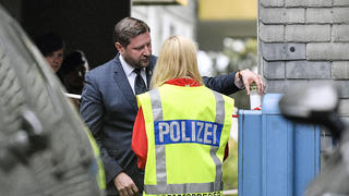 Solingen's mayor Tim Kurzbach puts a candle at the entrance of the house, where five dead children were found in Solingen, Germany, Thursday, Sept. 3, 2020. Police say five children have been found dead at an apartment in a western German city, and their mother is suspected of killing them. The bodies of three girls and two boys were found in Solingen, near Cologne and Duesseldorf on Thursday. (AP Photo/Martin Meissner)