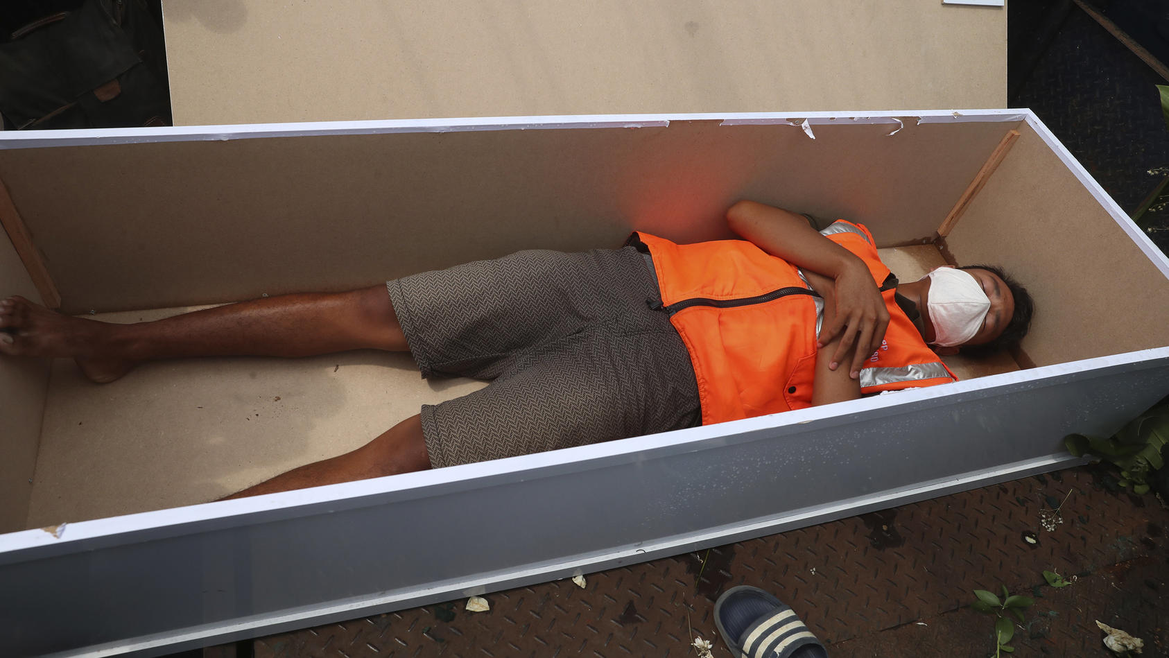A man lays inside a mock coffin as punishment for violating city regulations requiring people to wear face masks in public places as a precaution against the new coronavirus outbreak in Jakarta, Indonesia, Thursday, Sept. 3, 2020. (AP Photo/Achmad Ib