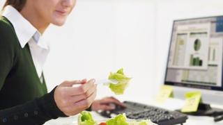 cropped view of woman eating salad in office. Copy space