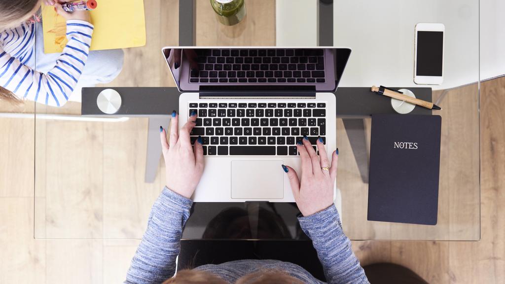 Woman typing on laptop at glass table while little girl drawing picture beside, top view model released Symbolfoto property released PUBLICATIONxINxGERxSUIxAUTxHUNxONLY IGGF00012