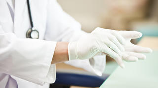Arzt zieht Einmalhandschuhe an