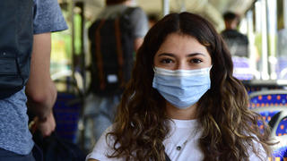 Eine Schülerin wartet an der Gemeinschaftsschule Bellevue in Saarbrücken auf den Schulbus und trägt für die Fahrt einen Mund-Nasen-Schutz, wie es die Corona-Hygieneregeln vorschreiben.