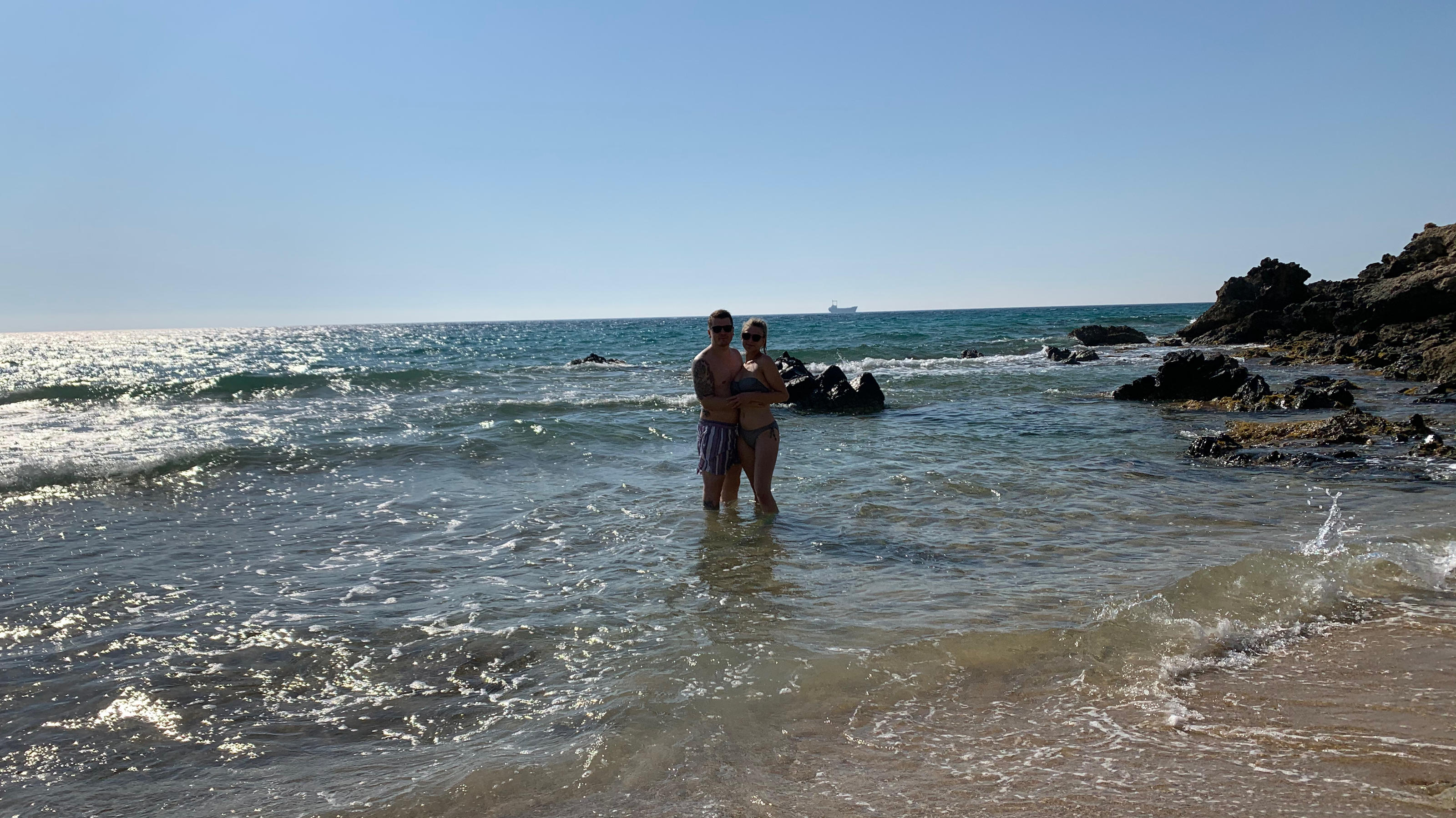 Paar steht am Strand in kniehohem Wasser