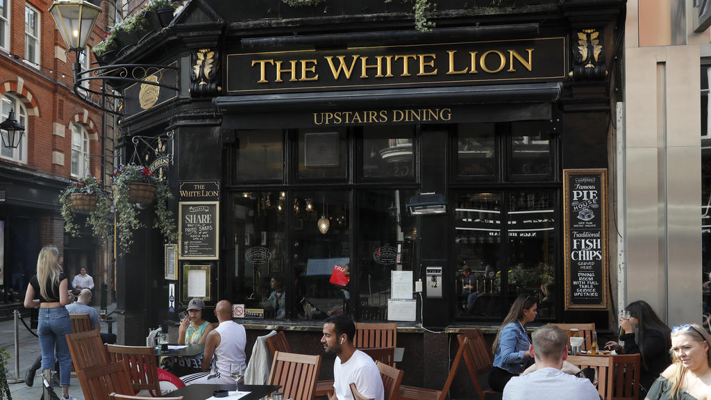 People sit outside the White Lion pub in London, Tuesday, Sept. 22, 2020. British Prime Minister Boris Johnson has slammed the brakes on the country's return to offices, saying people should work from home if possible to help slow the spread of the c