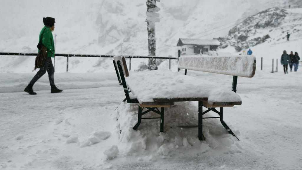 Eine Frau geht über die verschneite Terrasse der Bergstation am Osterfelderkopf im Wettersteingebirge nach einem Temperatursturz.