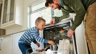 Vater und Sohn räumen Spülmaschine ein