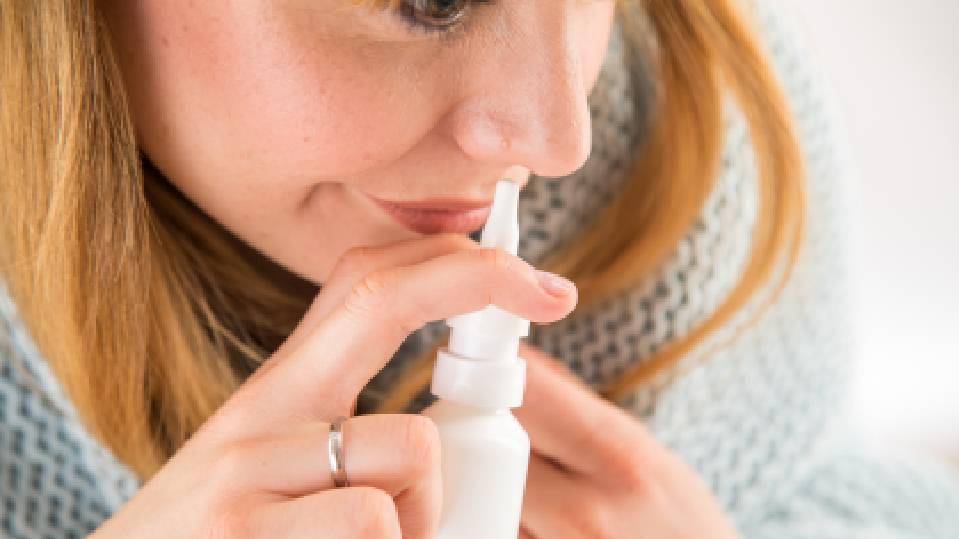 Junge Frau benutzt Nasenspray