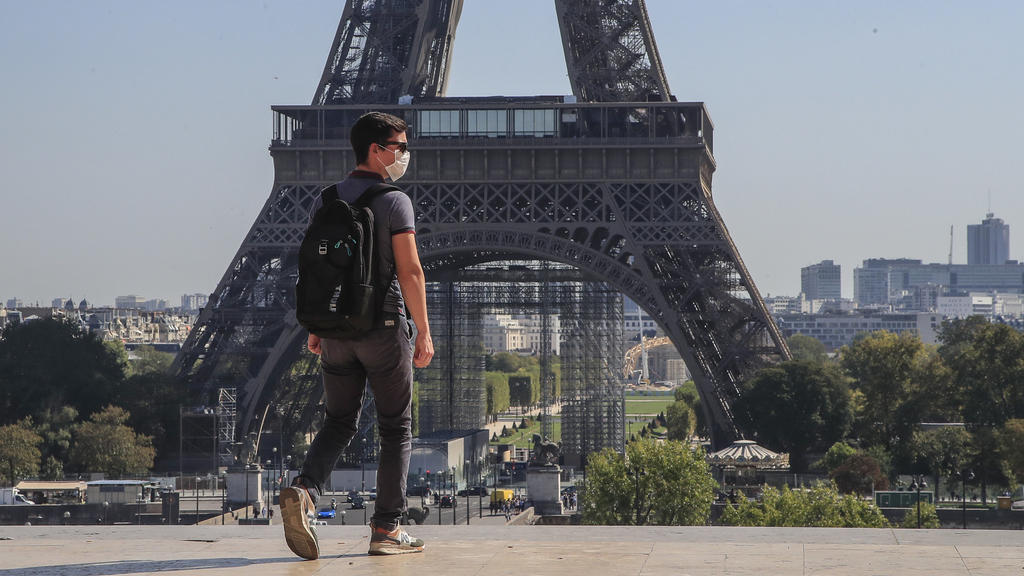Frankreich, Paris: Ein Passant geht mit Mundschutzmaske über den Place du Trocadéro, während im Hintergrund ein Teil des Eiffelturms zu sehen ist