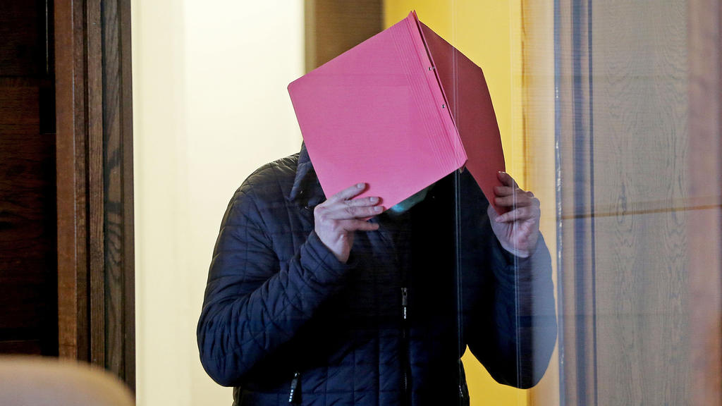 06.10.2020, Nordrhein-Westfalen, Köln: Der Angeklagte im Prozess wegen schweren sexuellen Missbrauchs von Kindern kommt in den Gerichtssaal, während er sich eine Mappe vor das Gesicht hält. Im Missbrauchskomplex Bergisch Gladbach ist der Angeklagte z