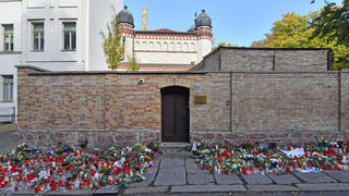 ARCHIV - 13.10.2019, Sachsen-Anhalt, Halle (Saale): Blumen und Kerzen stehen neben der Tür zur Synagoge, vier Tage nach dem rechtsextremistischen Anschlag auf die Gemeinde. Foto: Hendrik Schmidt/dpa-Zentralbild/dpa +++ dpa-Bildfunk +++