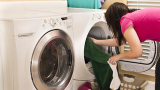 Frau holt Wäsche aus dem Trockner