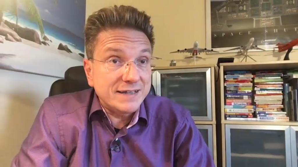Ralf Benkö an seinem Schreibtich in violettem Hemd
