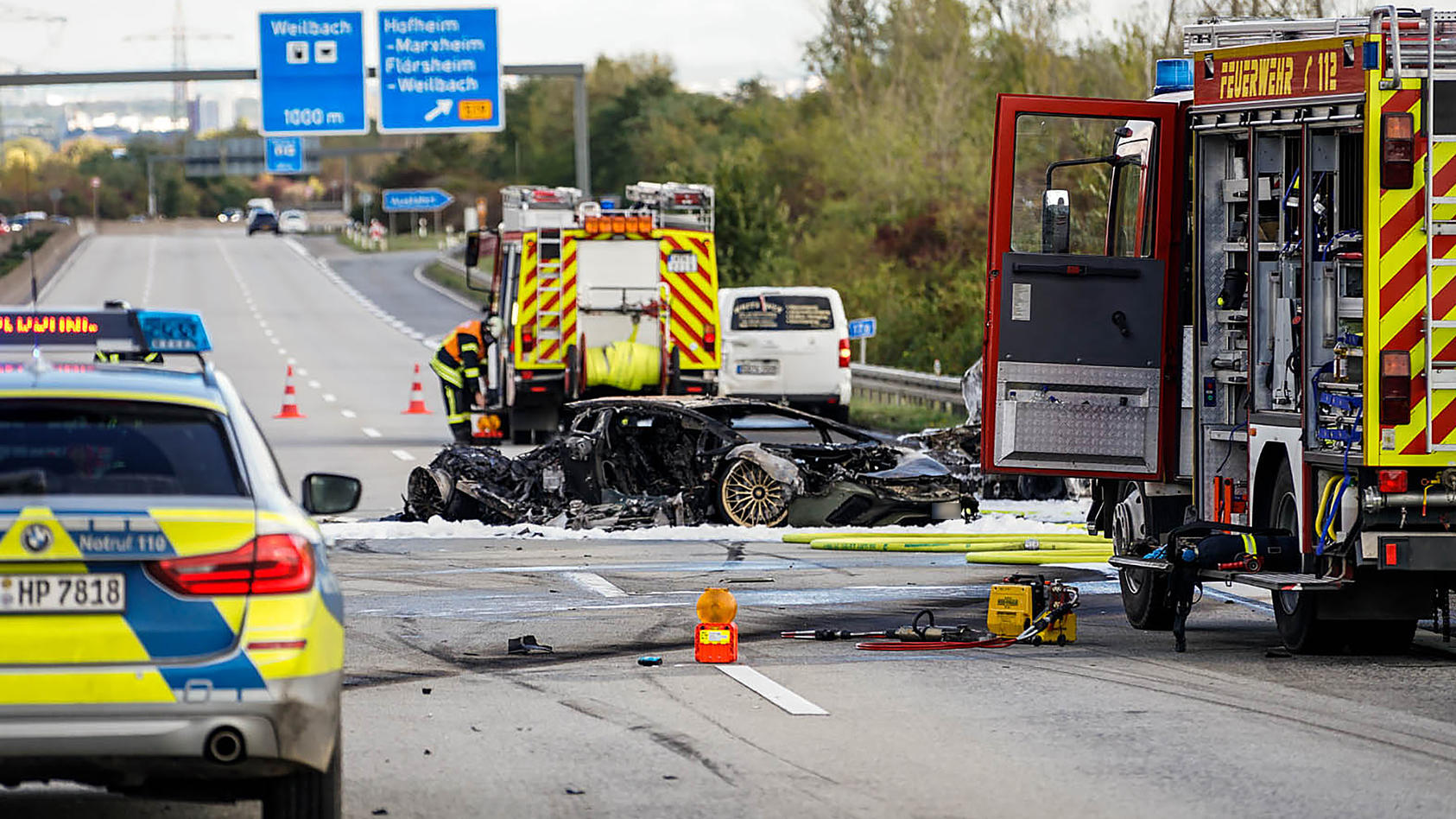 Hessen, Hofheim: Feuerwehrfahrzeuge stehen bei einem ausgebrannten Fahrzeug nach einem Unfall auf der Autobahn 66.