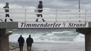 14.10.2020, Schleswig-Holstein, Timmendorfer Strand: Besucher sind an der Seebrücke am Timmendorfer Stand unterwegs, dahinter ist die aufgewühlte Ostsee zu sehen. Für die gesamte deutsche Ostseeküste ist ab Mittwochnachmittag eine Sturmflut vorhergesagt. Foto: Bodo Marks/dpa +++ dpa-Bildfunk +++