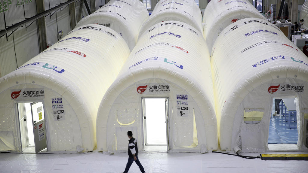 14.10.2020, China, Qingdao: Ein Mann geht an temporären COVID-19-Testverarbeitungslabors vorbei, die in aufblasbaren Zelten eingerichtet wurden. Nach einem neuen Ausbruch des Coronavirus hat die ostchinesische Metropole Qingdao innerhalb von vier Tag