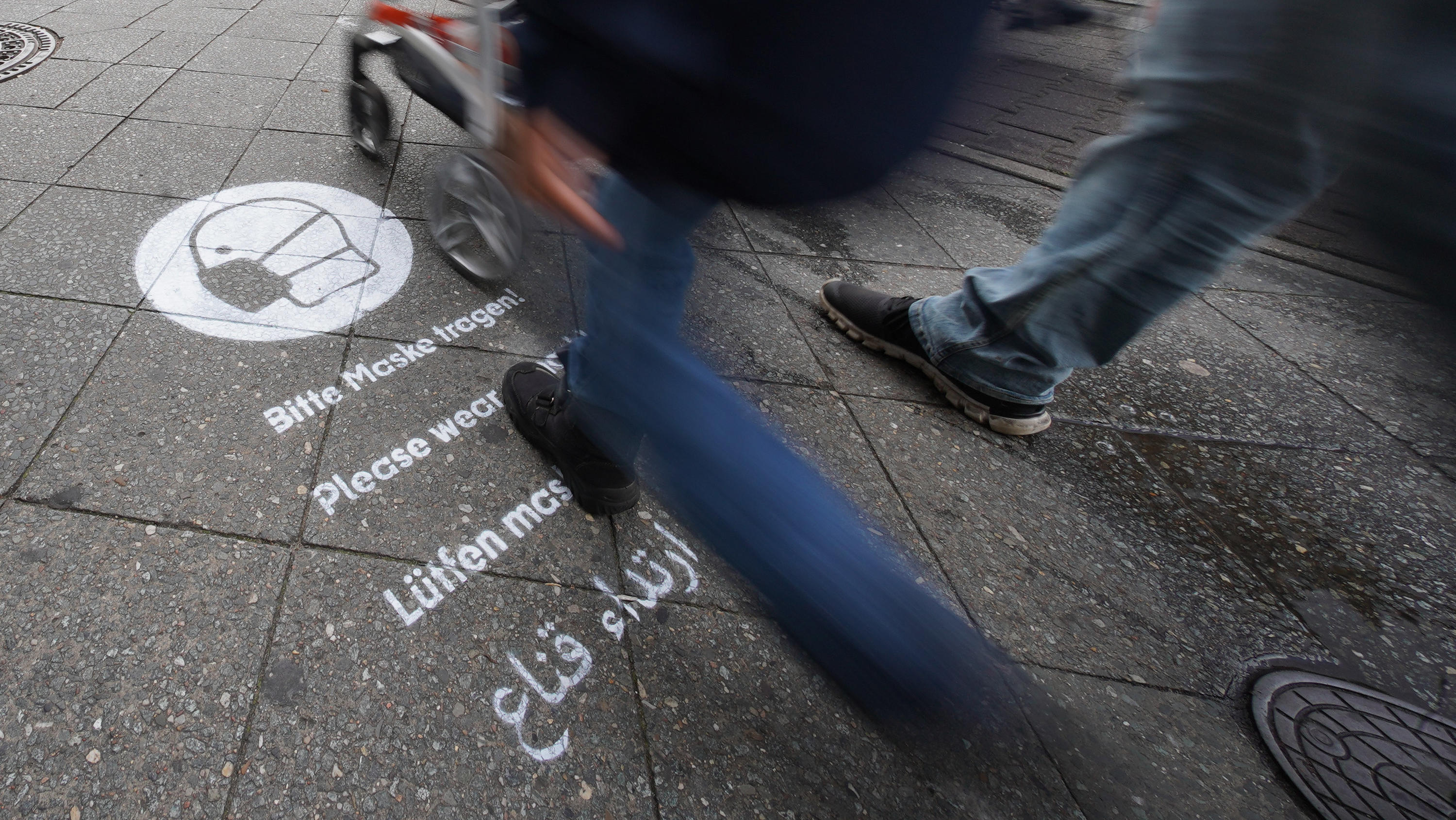 24.10.2020, Berlin: Ein Graffiti mit dem Hinweis, dass eine Maske zu tragen ist, ist auf dem Gehweg der Karl-Marx-Straße gesprüht. Zur Eindämmung der Corona-Pandemie wird die Maskenpflicht in Berlin ausgeweitet. Ab sofort gilt dies auch für belebte E
