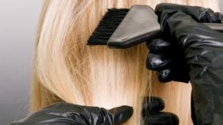 hairdresser doing hair dye. photo against grey background