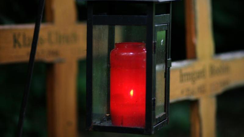 Ein Grablicht leuchtet auf einem Friedhof