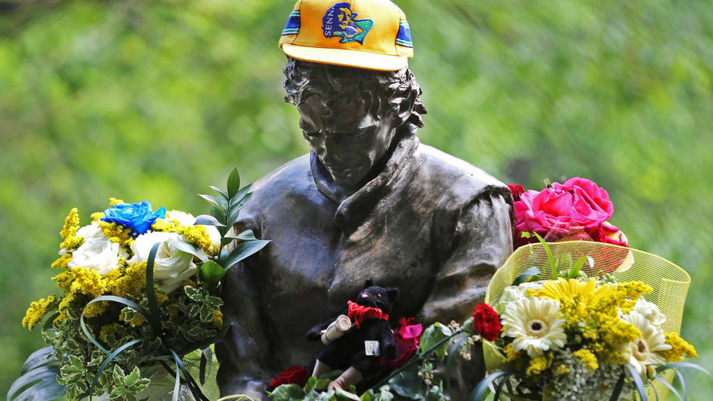 ARCHIV - 01.05.2014, Italien, Bologna: In einem Park nahe der Formel-1-Rennstrecke in Imola erinnert eine mit Blumen geschmückte Statue an den tödlich verunglückten Rennfahrer Ayrton Senna. Der Brasilianer war 1994 in Imola bei einem Unfall gestorben