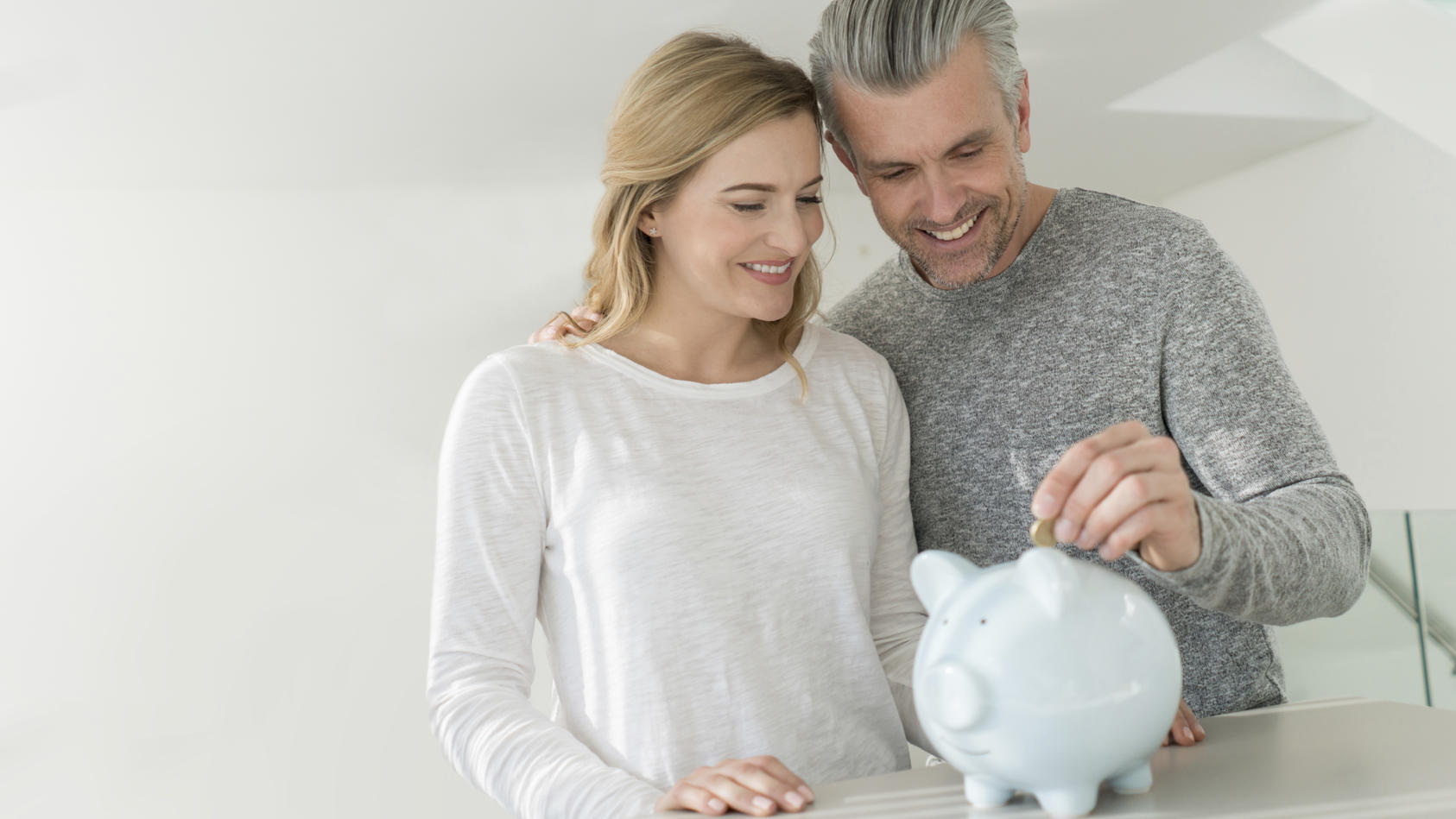 Loving couple saving money in a piggybank and looking happy - home finances concepts