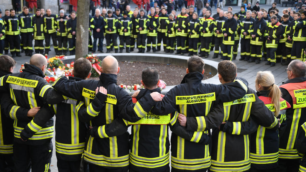ARCHIV - 08.12.2019, Bayern, Augsburg: Am Königsplatz in Augsburg trauern Feuerwehrmänner. Ein Mitglied der Berufsfeuerwehr war am Abend des 06.12.2019 in seiner Freizeit in einer Auseinandersetzung mit einer Gruppe Jugendlicher so schwer verletzt wo