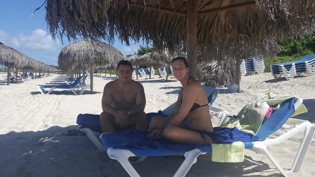 Mann und Frau sitzen jeweils auf Strandliege unter Sonnenschirm