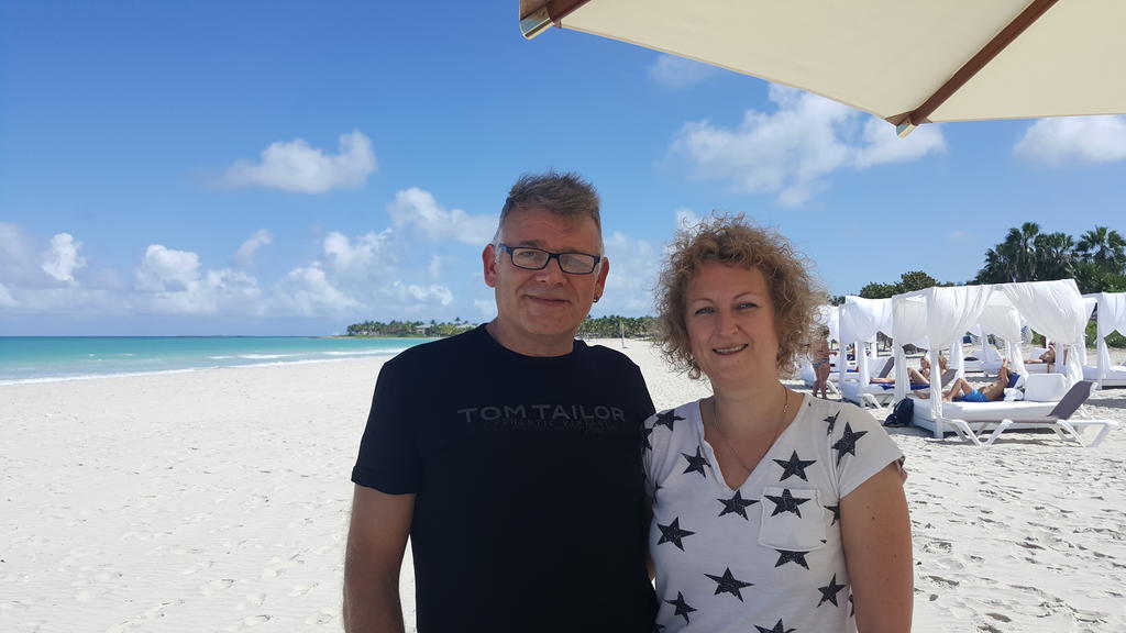 Mann und Frau stehen am Strand unter Sonnenschirm