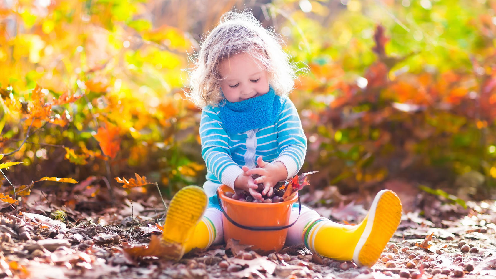 Kleines Mädchen spielt mit Blättern.
