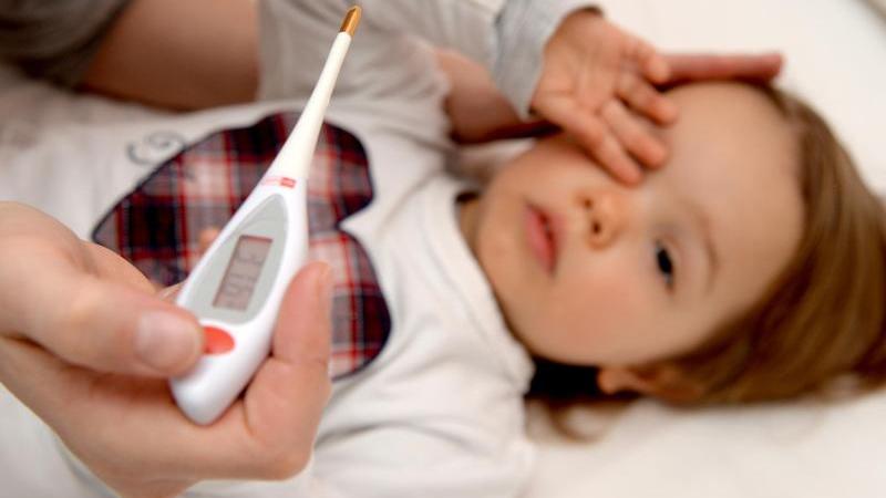 Bei einem Kind wird Fieber gemessen