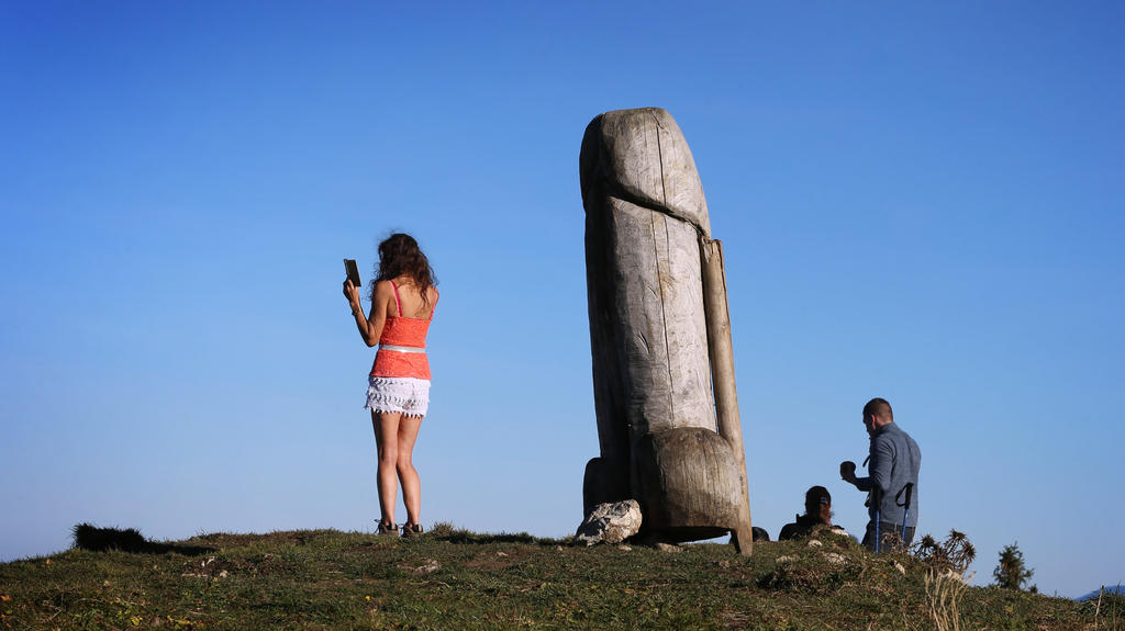 14.11.2020, Bayern, Rettenberg: Eine Frau macht ein Selfie mit der zwei Meter hohen Penis-Skulptur aus Holz auf dem Grat des Grünten. Seit vier Jahren steht das ungewöhnliche «Kulturdenkmal» auf dem Berg. (zu dpa «Kulturdenkmal»: Holzpenis auf Allgäu
