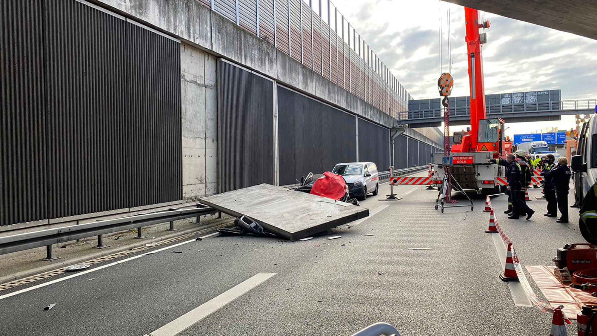 HANDOUT - 13.11.2020, Nordrhein-Westfalen, Köln: Ein Betonteil einer Lärmschutzwand liegt auf der Autobahn 3 (A3) auf einem Pkw. Eine große Betonplatte einer Lärmschutzwand ist auf der Autobahn 3 bei Köln auf einen Wagen gestürzt und hat eine Autofah
