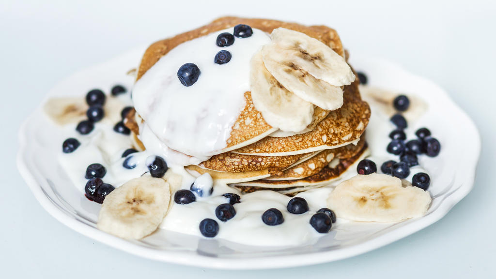 Hausgemachte Pfannkuchen mit Banane, Heidelbeeren und Sauerrahm