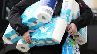 ARCHIV - 18.03.2020, Nordrhein-Westfalen, Siegen: Ein Mann trägt eingekauftes Toilettenpapier und Küchenrollen aus einem Supermarkt. Der Verkauf von Toilettenpapier ist in der vergangenen Woche drastisch zurückgegangen. Erstmals seit Beginn der Corona-Krise habe er unter dem Durchschnittswert der vorausgegangenen sechs Monate gelegen, teilte das Statistische Bundesamt am 08.04.2020 mit. Foto: Rene Traut/dpa +++ dpa-Bildfunk +++
