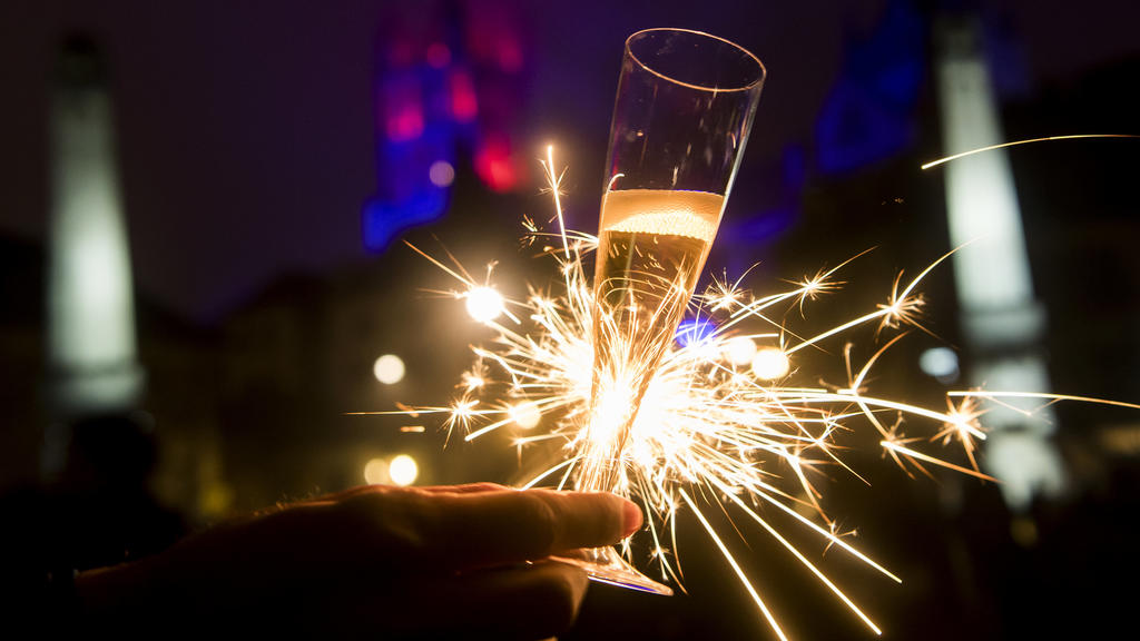 ARCHIV - 01.01.2017, Schweiz, Lausanne: Mit einem Glas Champagner und einer Wunderkerze in der Hand feiert eine Frau den Jahreswechsel. Kommt das Böllerverbot zu Silvester oder nicht? Wenn es um die Feiertage geht, scheint vielen in Deutschland Weihn